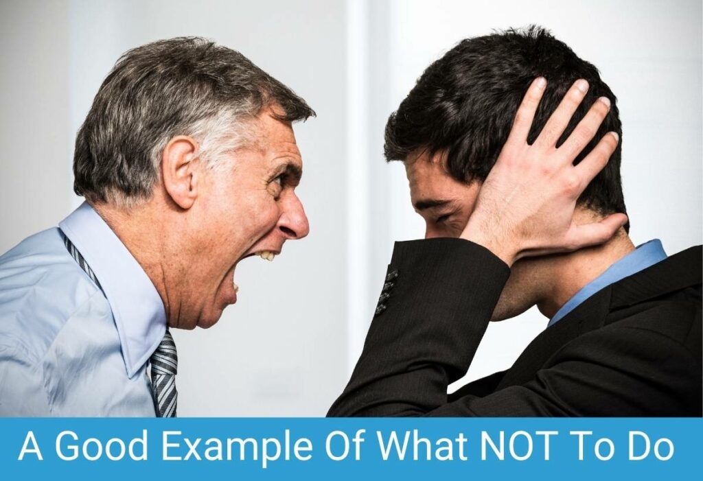 Older boss yelling at employee who has hands over his ears. "A Good Example of What NOT To Do"